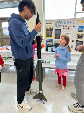 A team member showing a rocket to a young learner